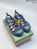 Dark gray KEEN-style closed-toe sandals with multicolor straps on a shoebox