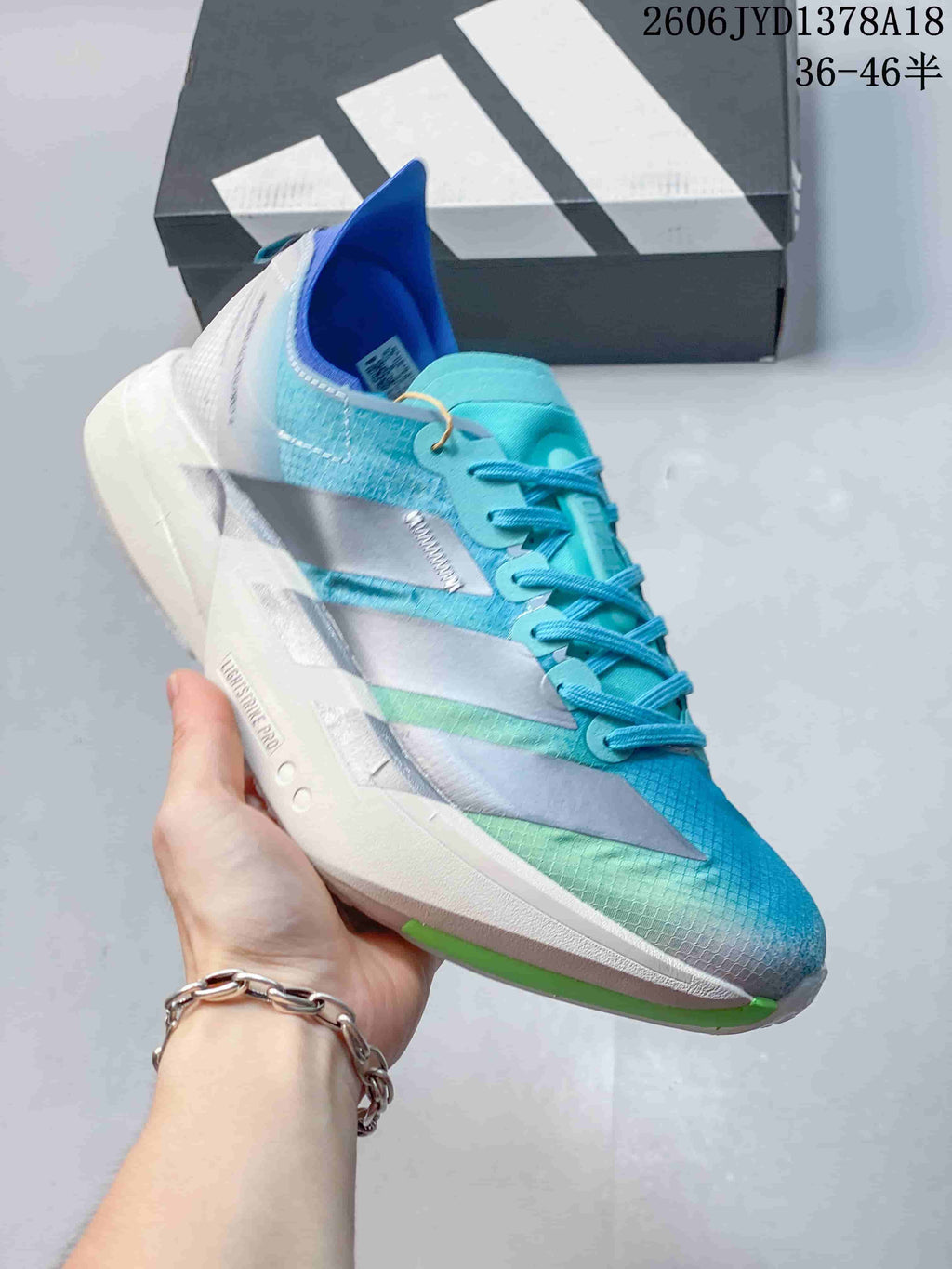 Angled side view of a blue and turquoise running shoe with silver stripes and green outsole accents