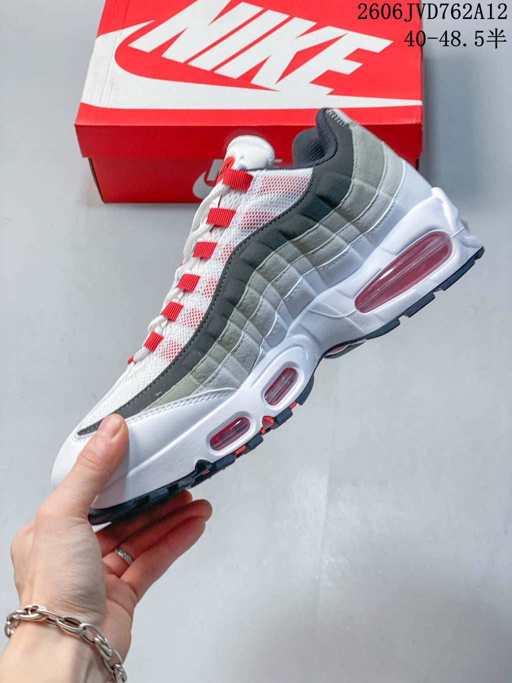 Side profile of a Nike Air Max 95 OG sneaker with layered gray panels and visible midsole windows.