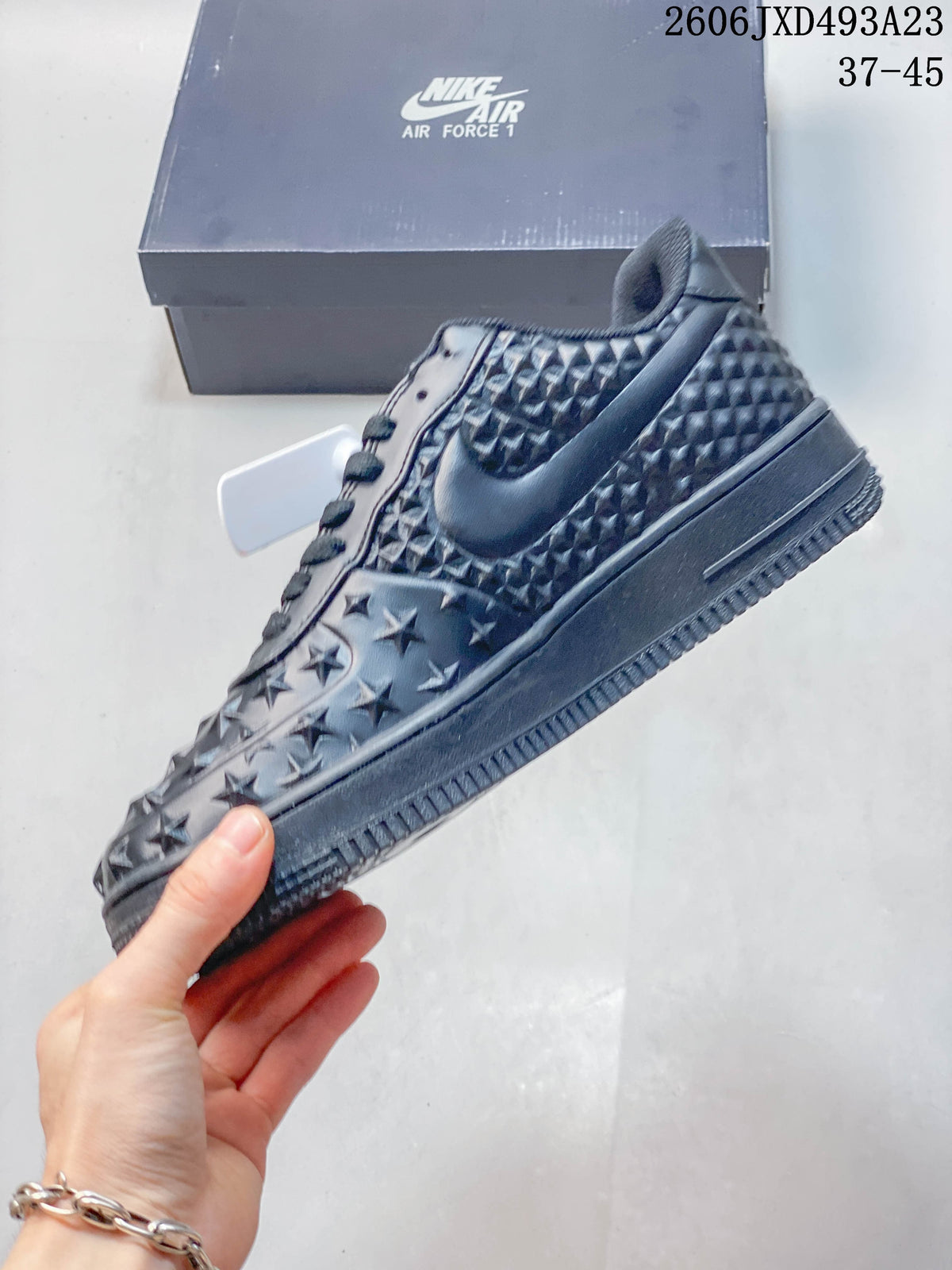 Side view of a dark low-top sneaker with raised star details and tonal Swoosh