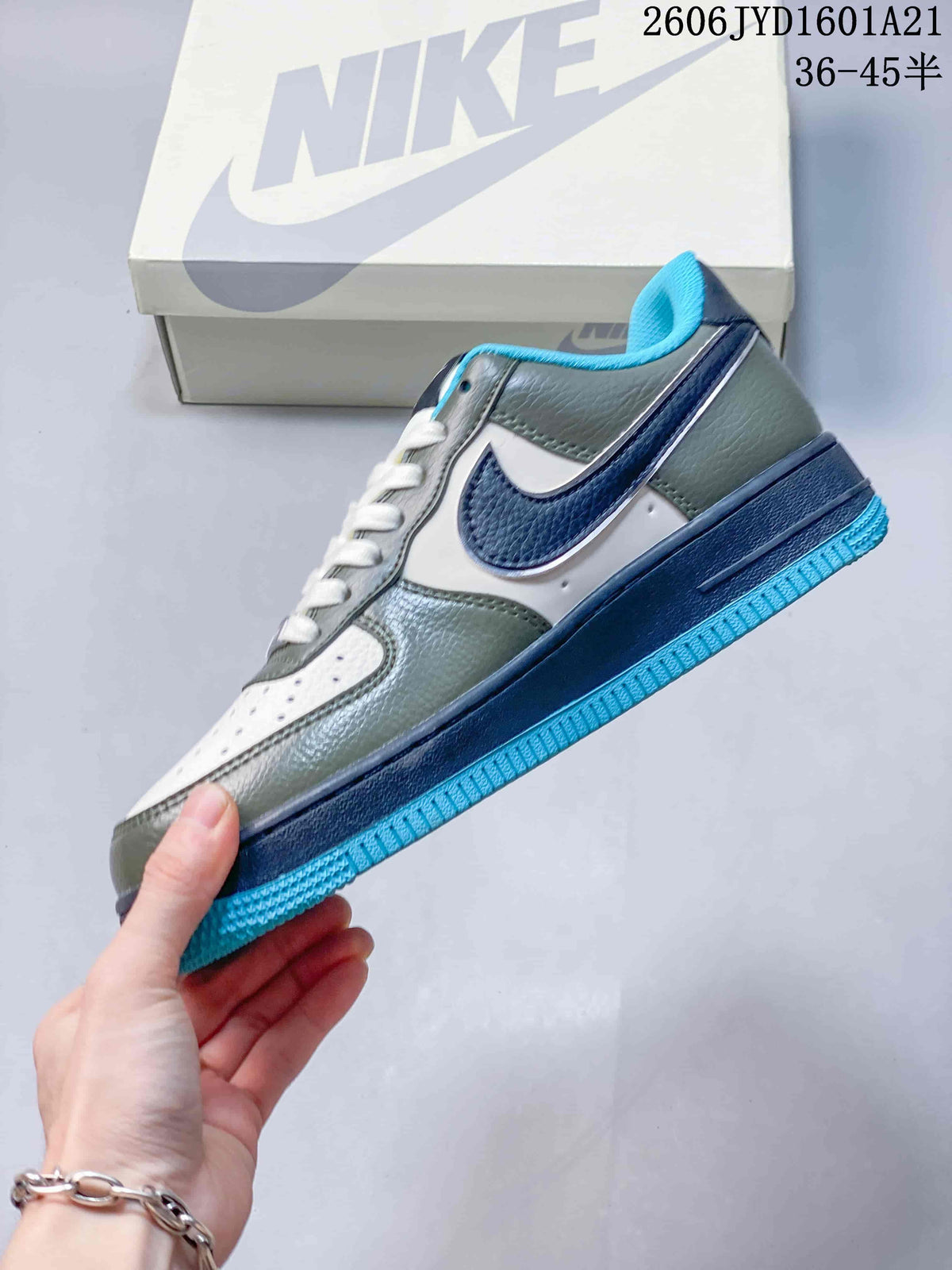 Side view of a low-top sneaker with white panels, muted green overlays, a navy Swoosh, and a bright blue outsole.