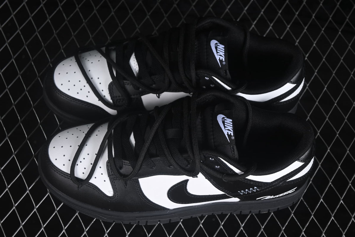 Top view of a pair of black and white low-top sneakers with perforated white toe boxes and black laces.