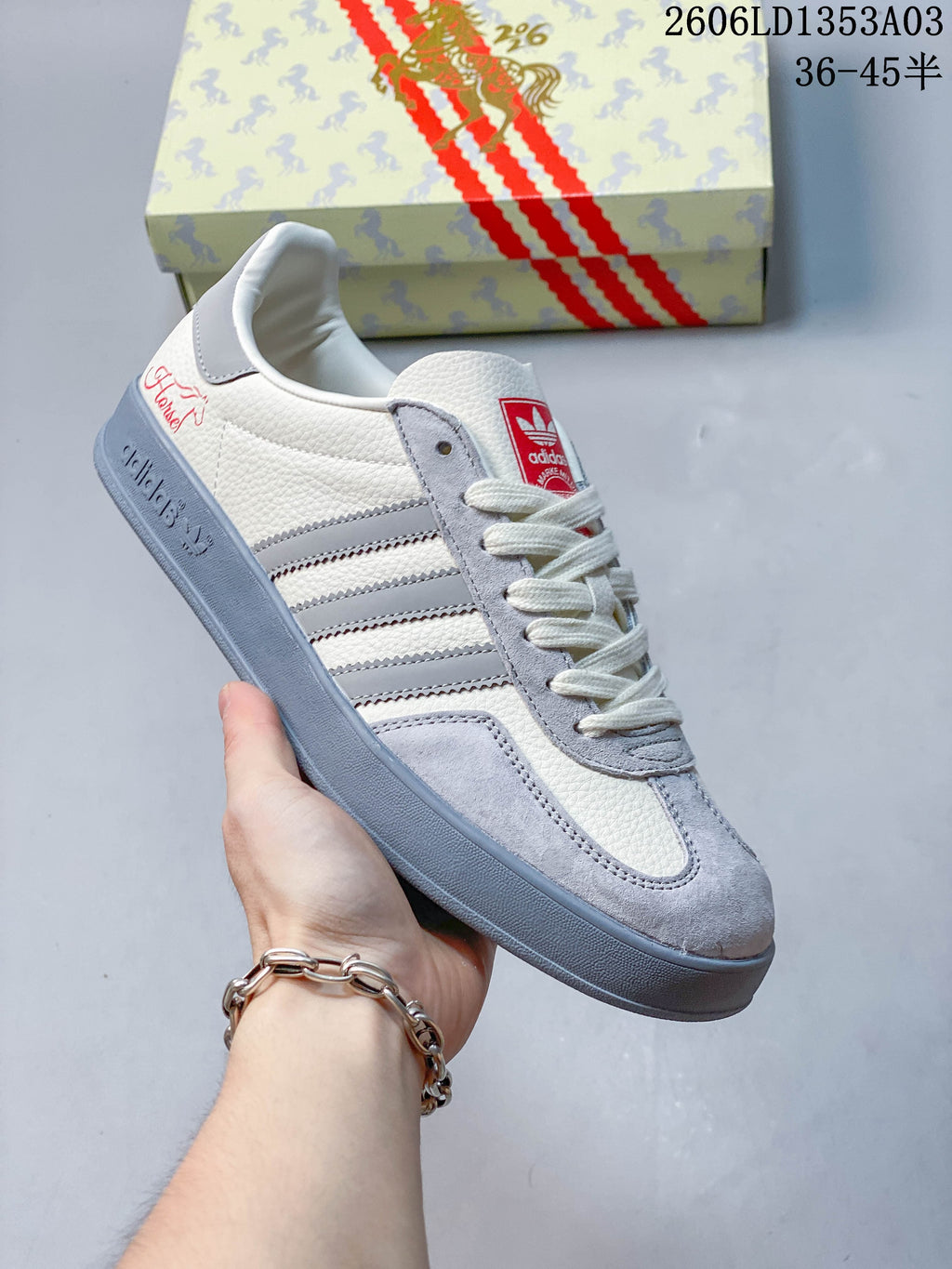 Angled side view of a white and grey low-top sneaker with three side stripes