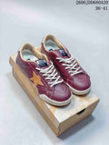 Pair of burgundy Golden Goose Super-Star low-top sneakers with tan stars and white laces, displayed on a shoebox