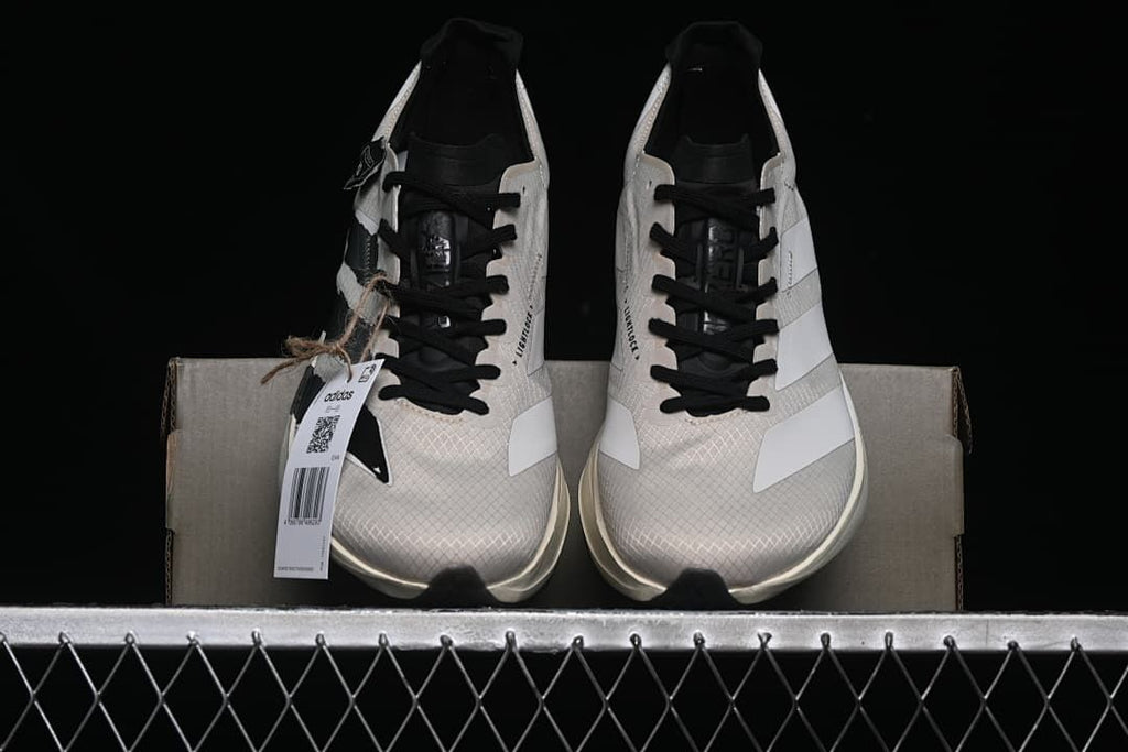 Front view of the pair of beige and white running shoes displayed on a box