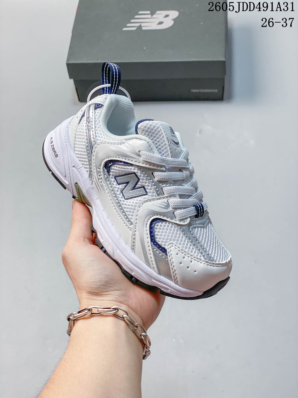 Angled side view of a white and navy New Balance 530 kids' sneaker.