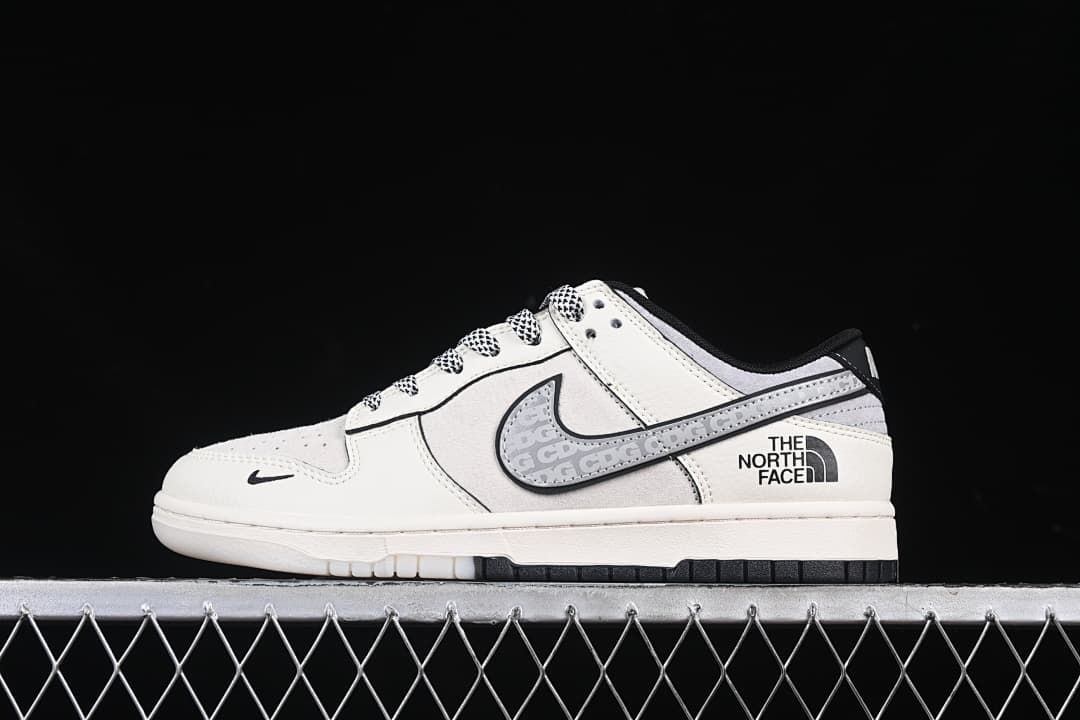 Side profile of an off-white and grey low-top Dunk with patterned laces, black accents, and The North Face heel branding