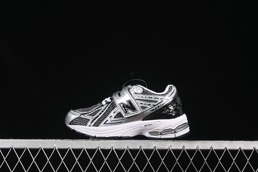 Side view of a single silver and black New Balance 1906R kids sneaker