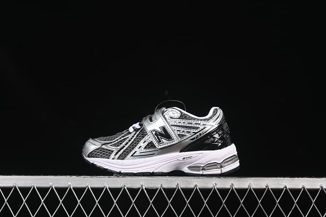 Side view of a single silver and black New Balance 1906R kids sneaker