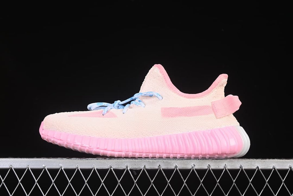 Side view of the pale pink sneaker with blue laces and a ribbed pink sole.