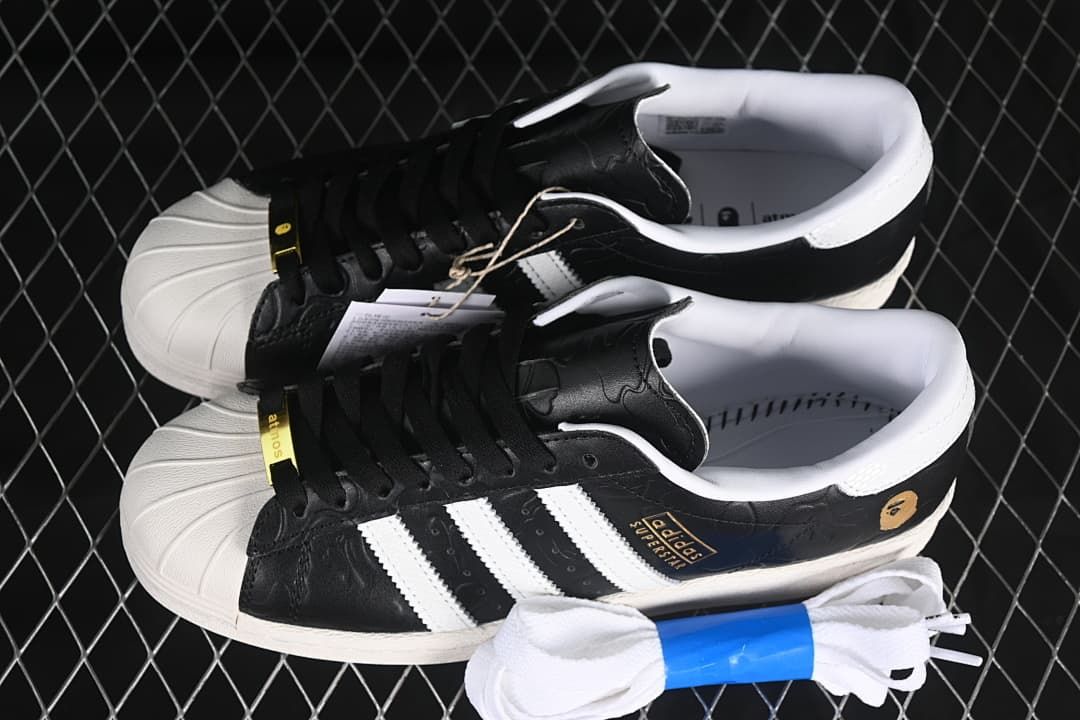 Pair of black and white Superstar sneakers with an extra set of white laces