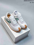 Pair of white and light gray low-top sneakers with green side detailing and gum-colored soles