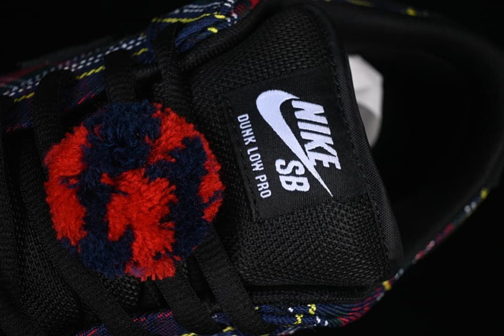 Close-up of the tongue label reading Nike SB Dunk Low Pro and a fuzzy red-and-navy lace detail.