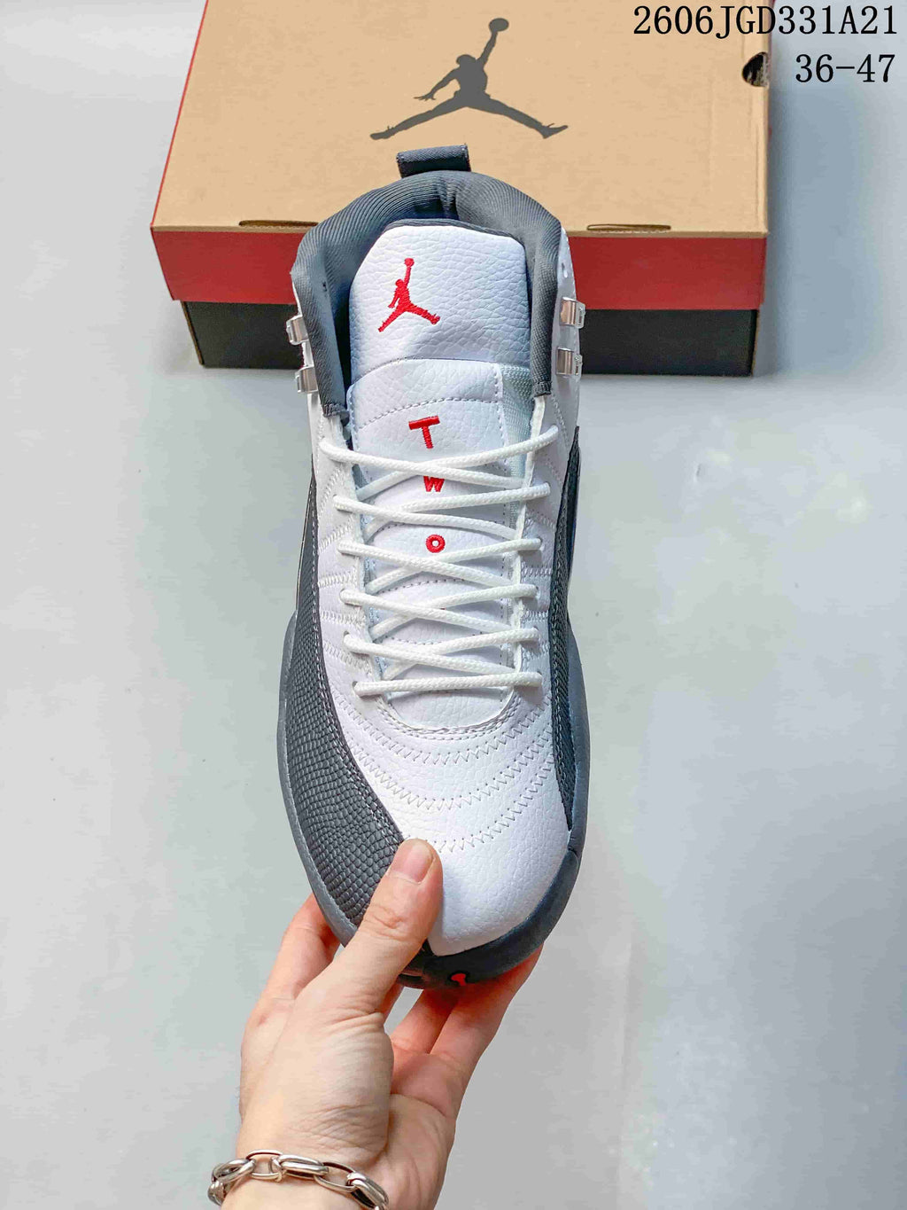 Front view of a white and grey Air Jordan 12 shoe with red accents