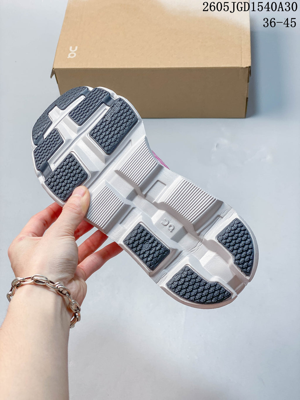 Underside of a white running shoe showing segmented dark outsole tread