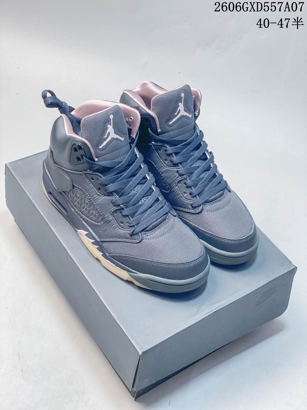 Pair of gray and navy Jordan Air Jordan 5 high-top sneakers with pale pink accents, shown on a gray box.