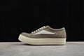 Side view of brown canvas low-top sneakers with cream laces and an off-white sole
