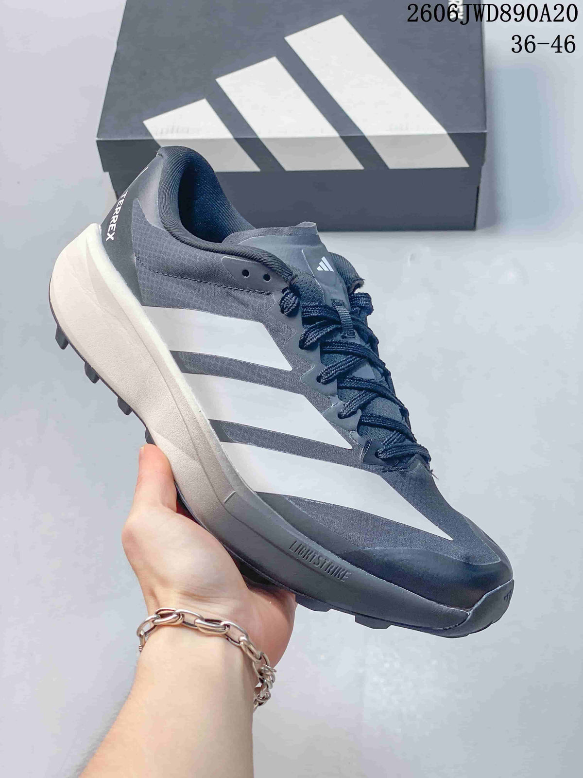 Side profile of the gray Terrex shoe showing the three-stripe detail and Lightstrike marking on the midsole.