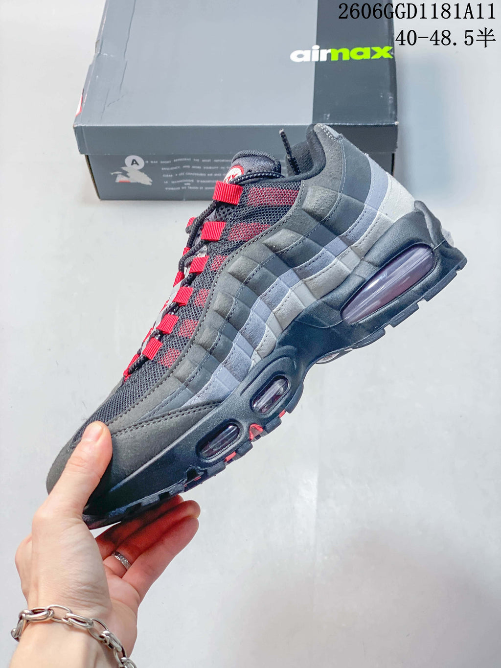 Side view of a grey Nike Air Max 95 OG sneaker with red accents and visible sole cushioning