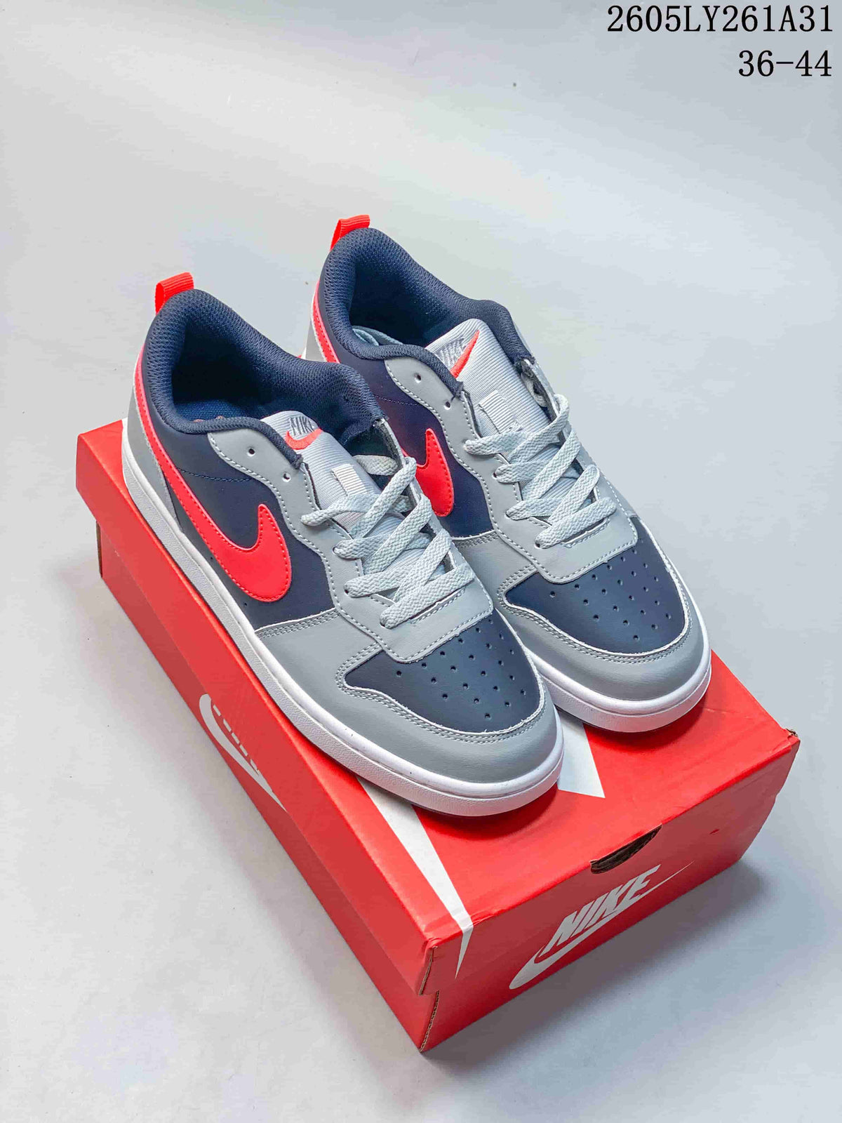 Pair of NikeCourt Borough Low Essential+ GS sneakers in navy, gray, red, and white, shown on a red shoe box