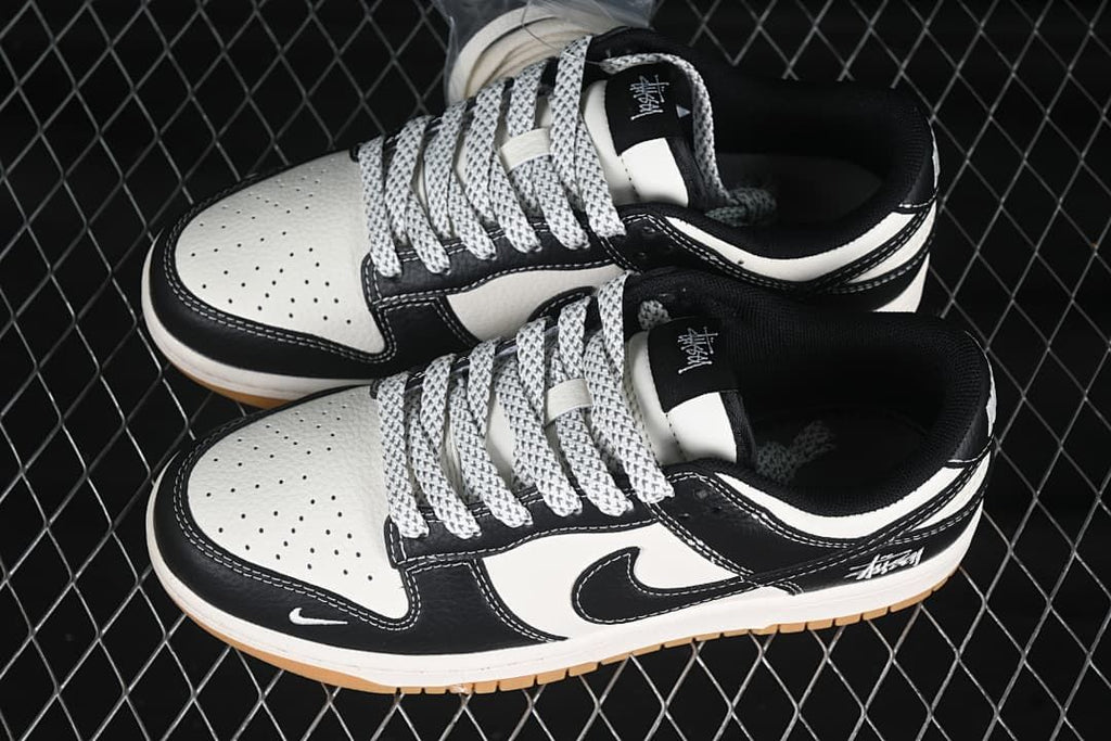 Top view of a pair of black and white low-top sneakers with patterned laces and heel script