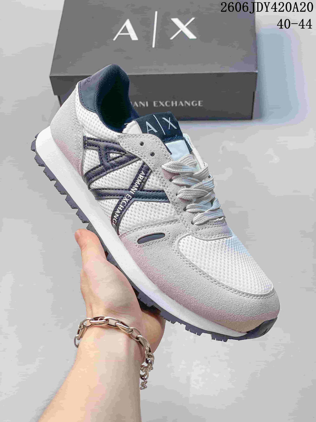 Angled side view of the white and gray Armani Exchange sneaker with navy accents