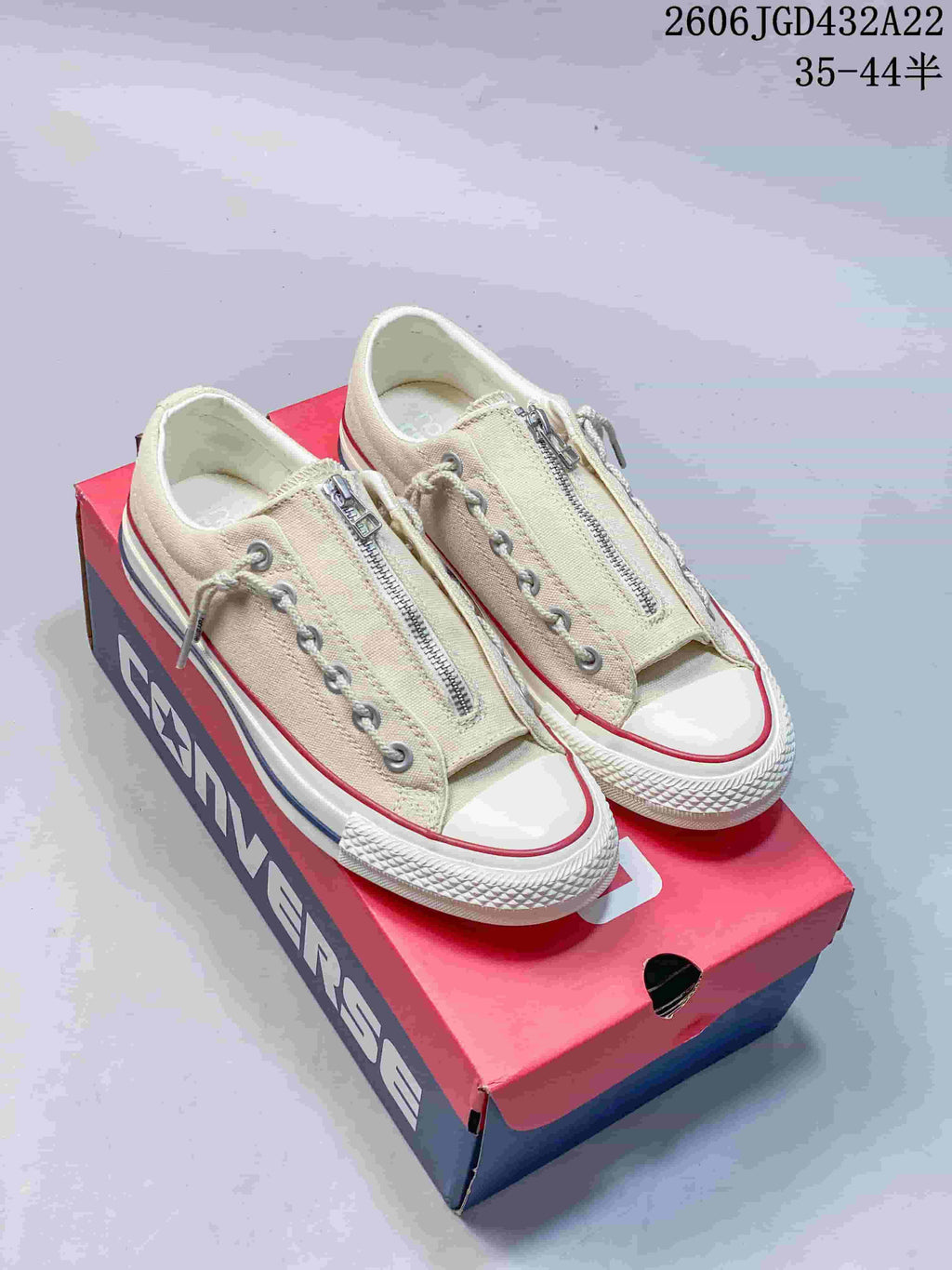 Light beige low-top Converse sneakers with front zippers and off-white soles on a Converse box