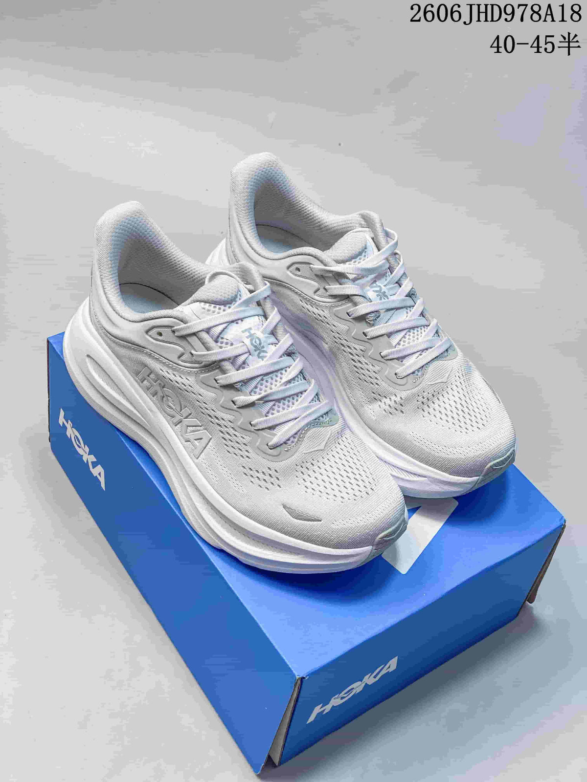 Pair of light gray-white HOKA Bondi 9 shoes on a blue shoebox