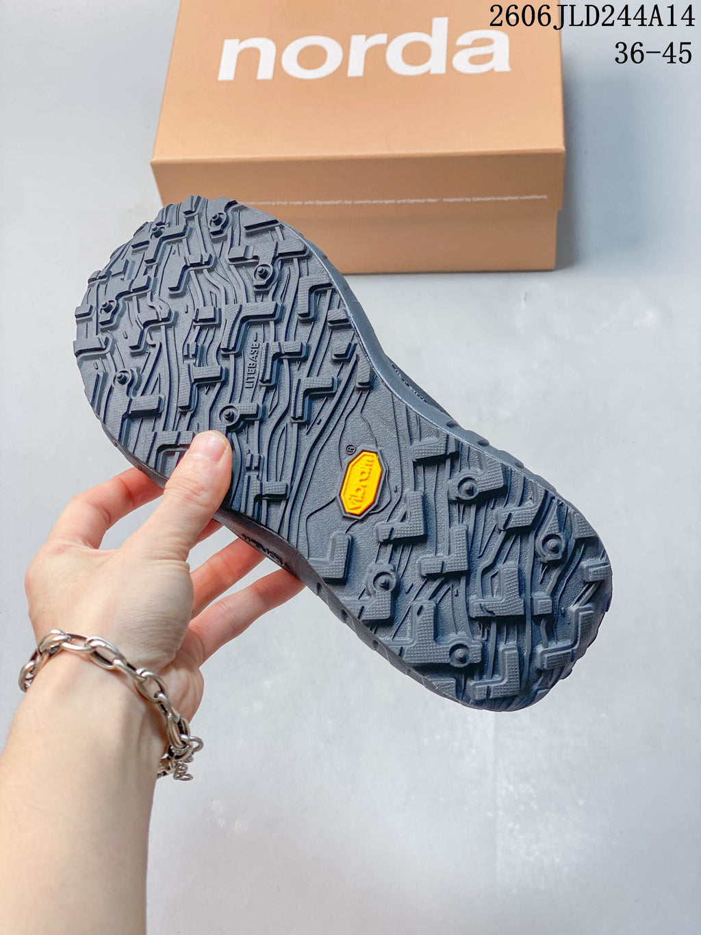Close-up of the norda shoe outsole showing a deep, patterned tread and a small yellow insert.