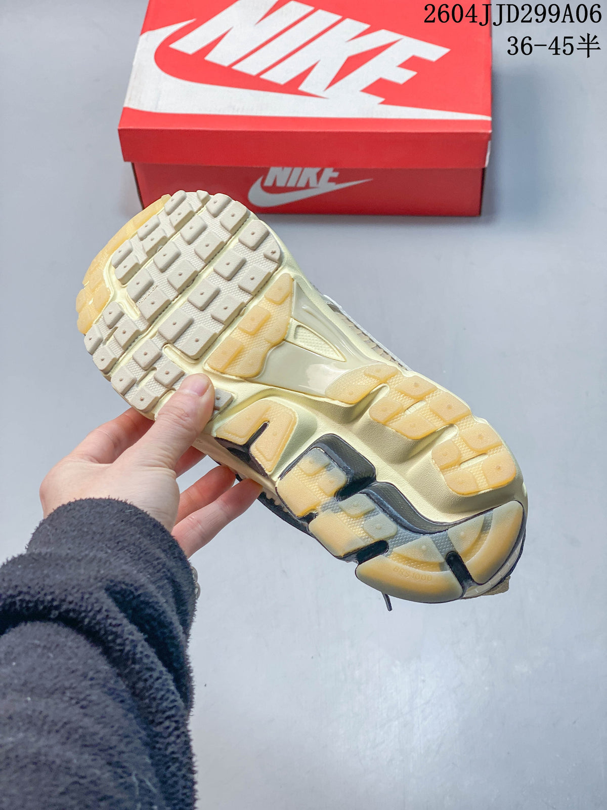 Outsole view of a Nike Zoom Vomero 5 sneaker, with a red shoe box in the background.