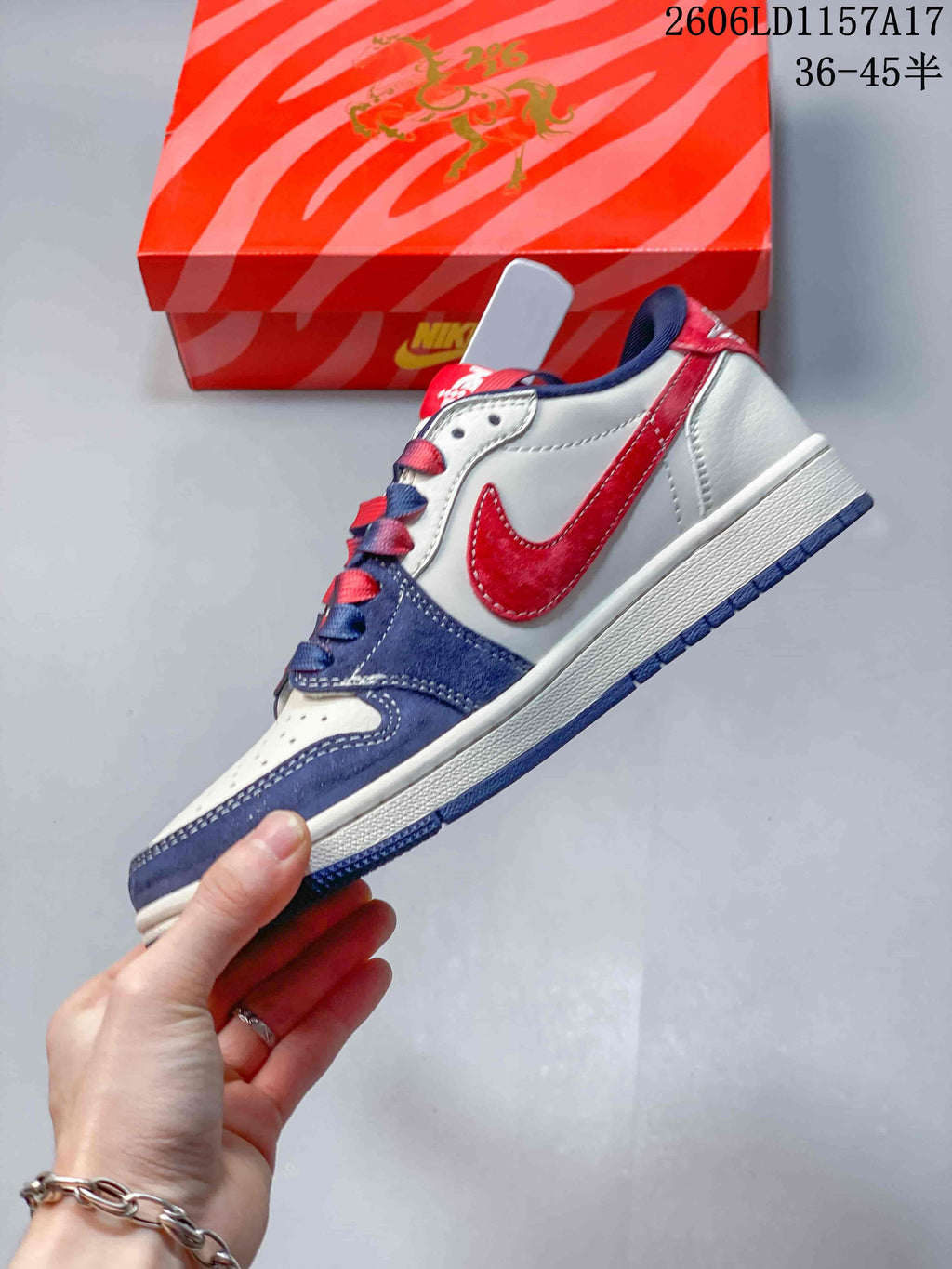 Side view of the low-top sneaker with a red side panel, navy overlays and white midsole.