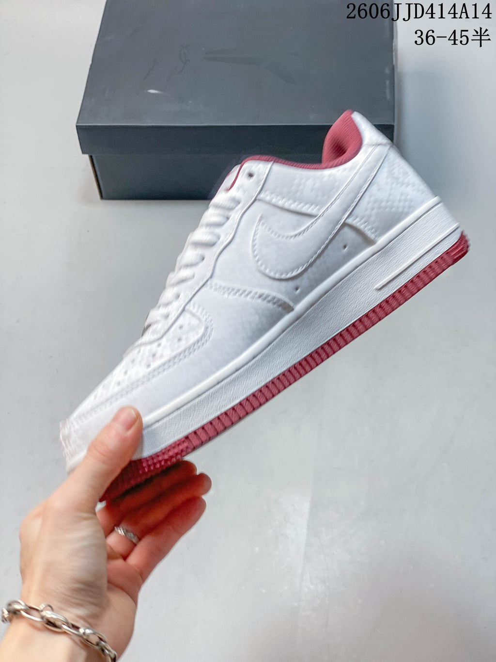 Side view of the white low-top sneaker with burgundy-red collar lining and outsole