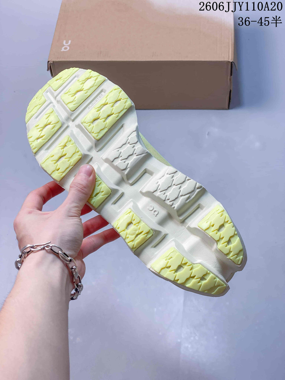 Outsole view of a pale yellow and white running shoe, showing segmented tread.