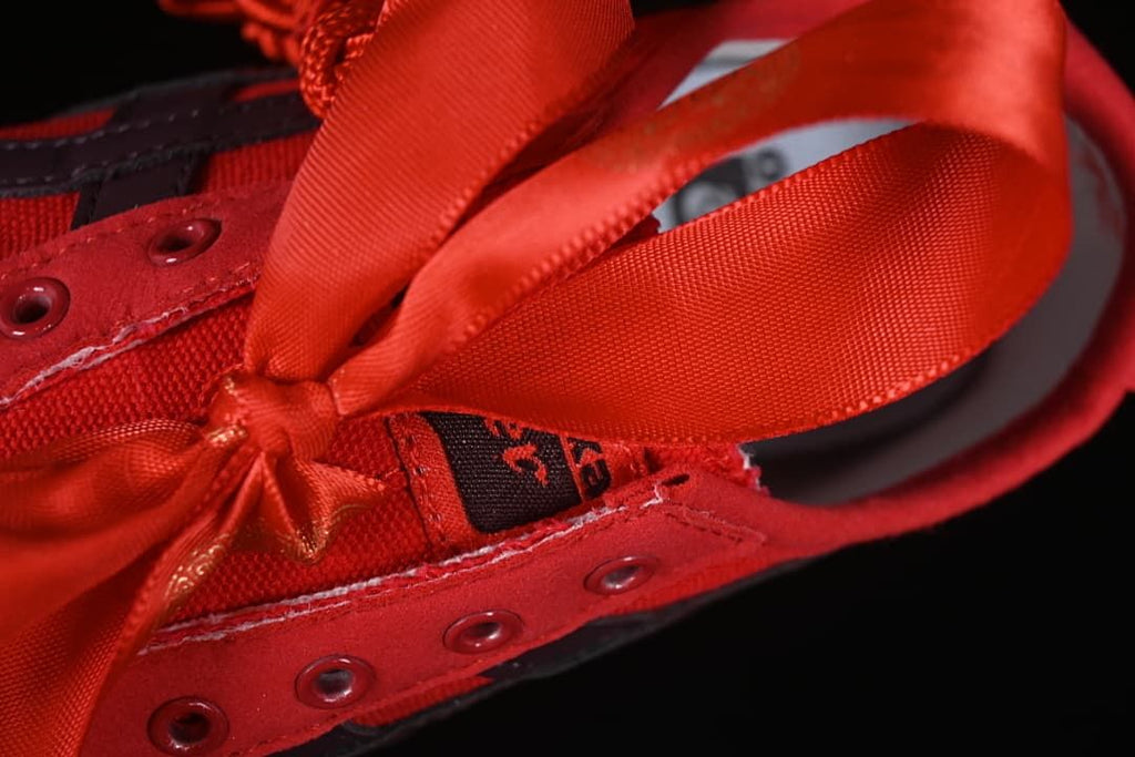 Close-up of the wide red ribbon laces and lace eyelets