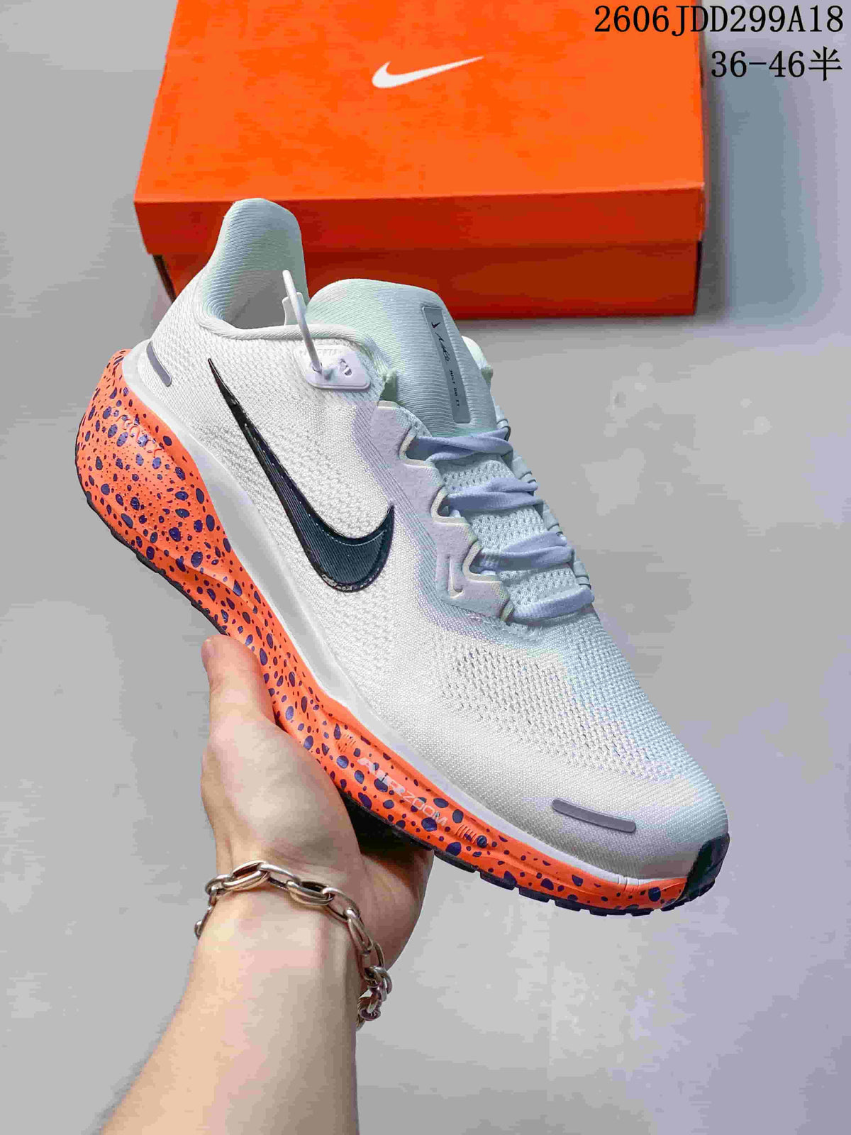 Angled side view of a white Nike running shoe with a dark Swoosh and orange speckled midsole.