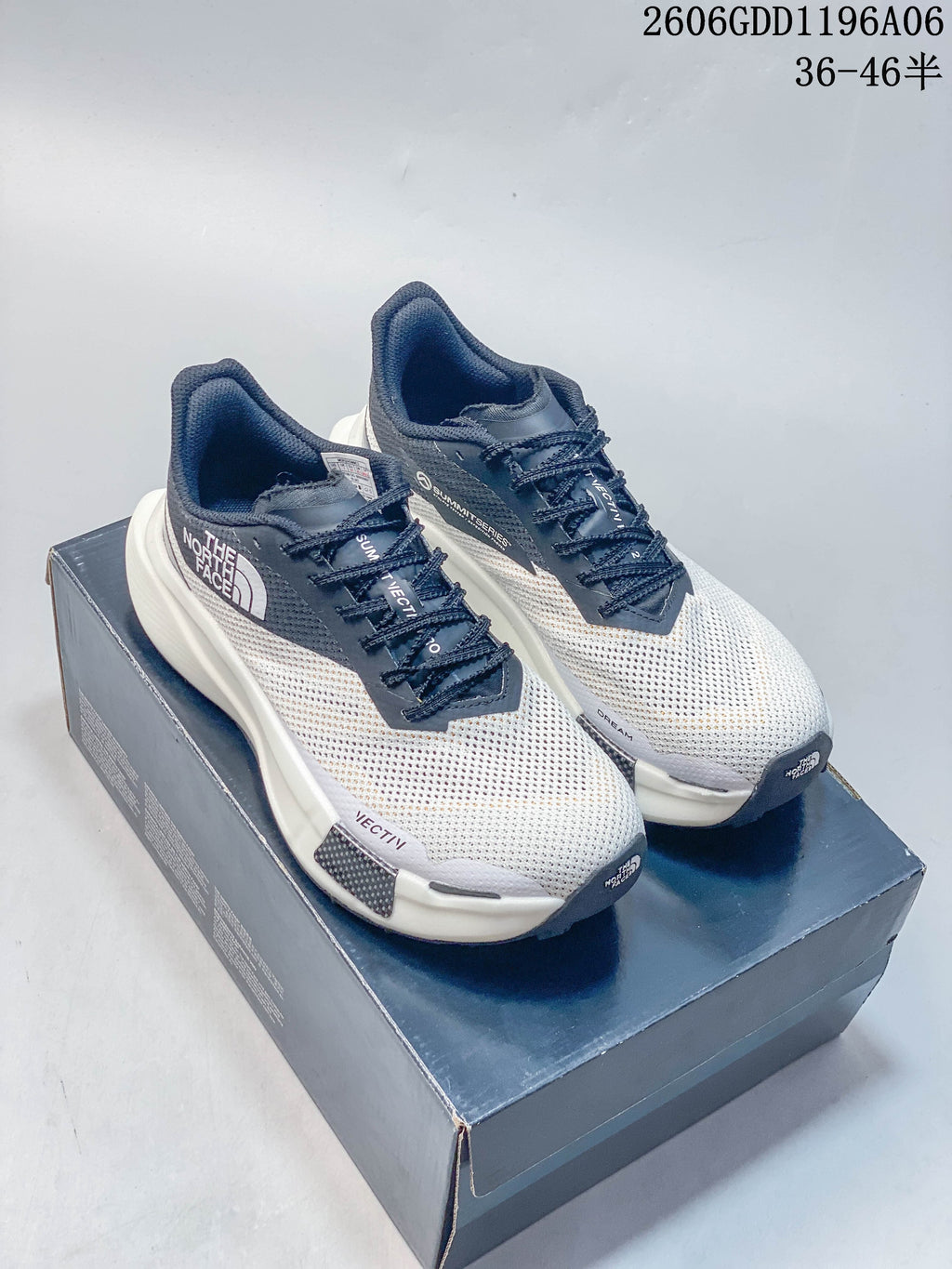White and gray mesh The North Face sneakers displayed on a shoebox.