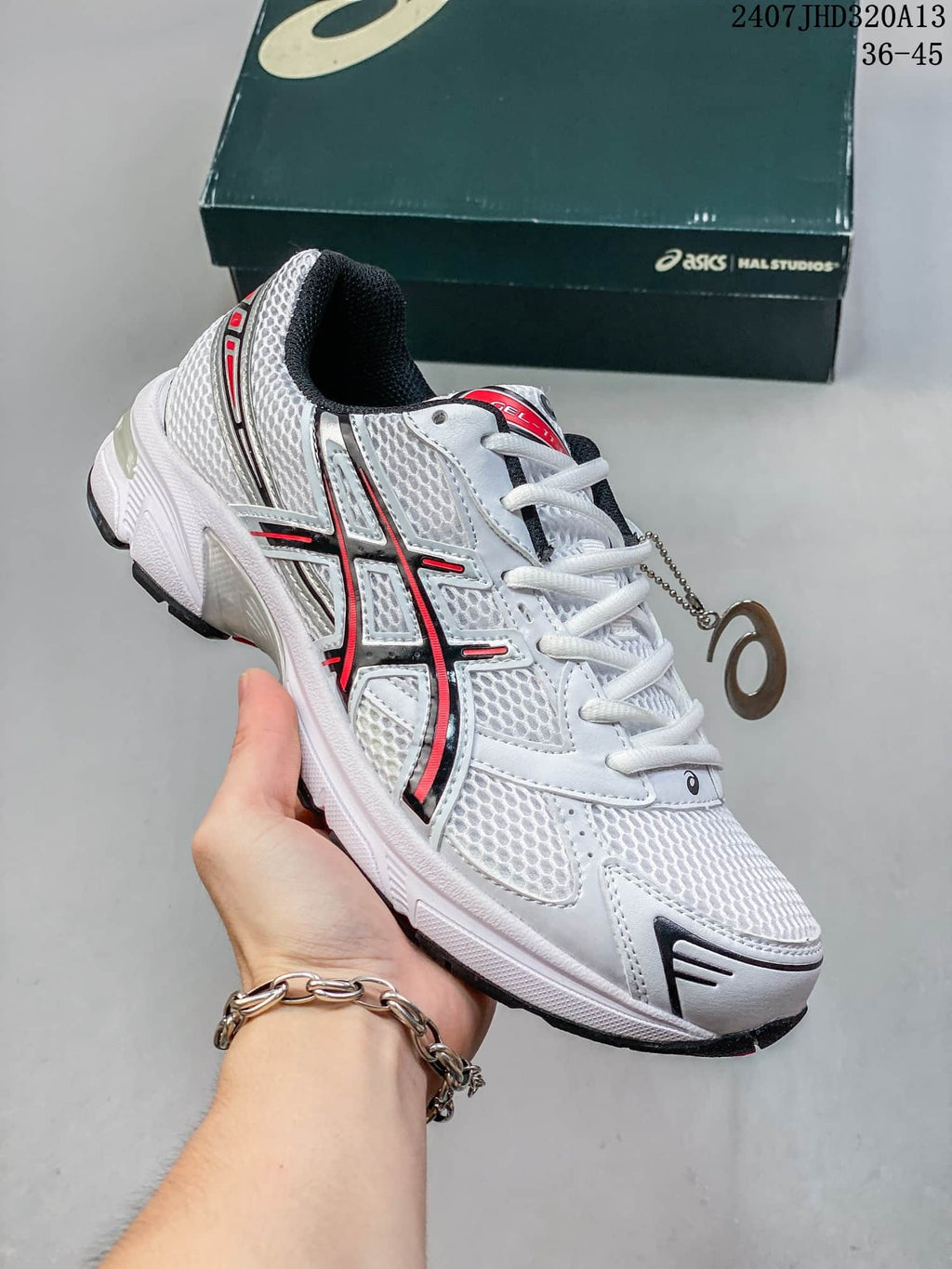 Angled side view of the white sneaker with black and red accents