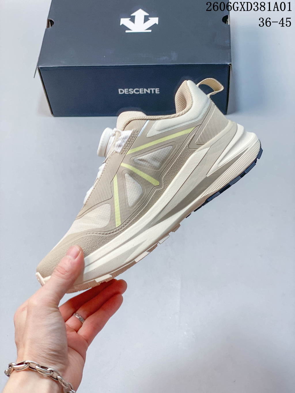 Side view of the beige DESCENTE sneaker with yellow-green accents and a dial closure