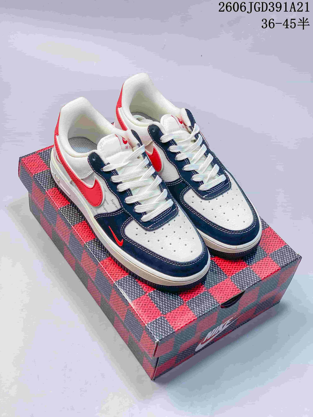 Pair of white low-top sneakers with navy and bright red accents and white laces.
