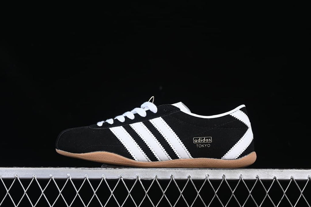 Side view of the black adidas Tokyo sneaker with white stripes and gum-colored sole