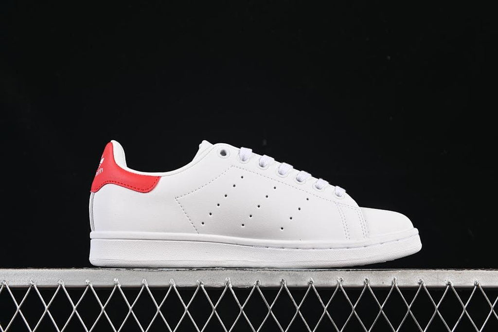 Side profile of the white low-top sneaker with red heel accent