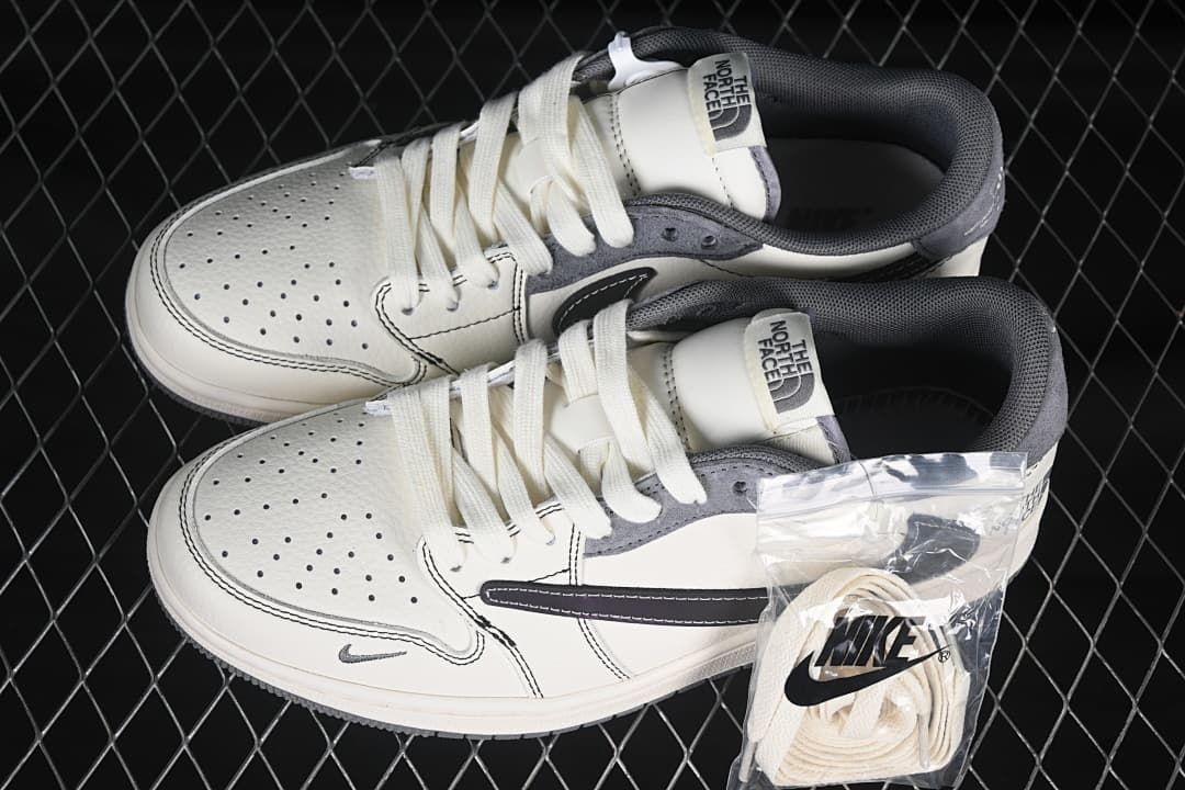 Top view of a pair of off-white and grey low-top sneakers with perforated toes, tongue branding, and an additional pair of laces.