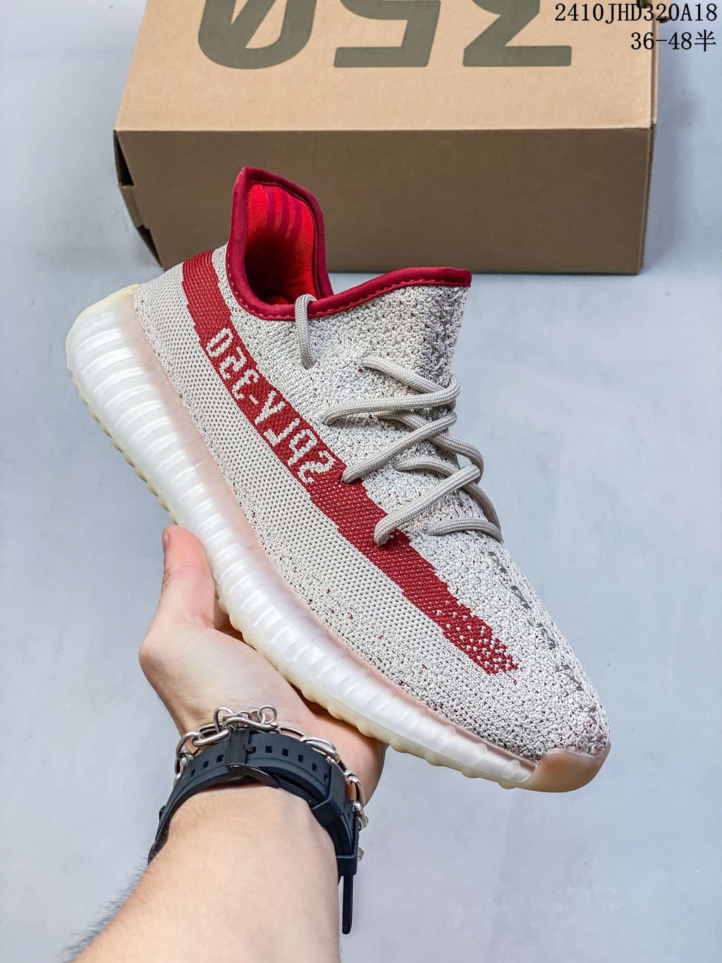Side view of a cream sneaker with a red stripe and ribbed sole