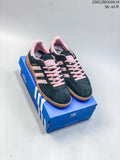 Pair of navy Adidas low-top sneakers with pink details and gum soles on a blue shoebox