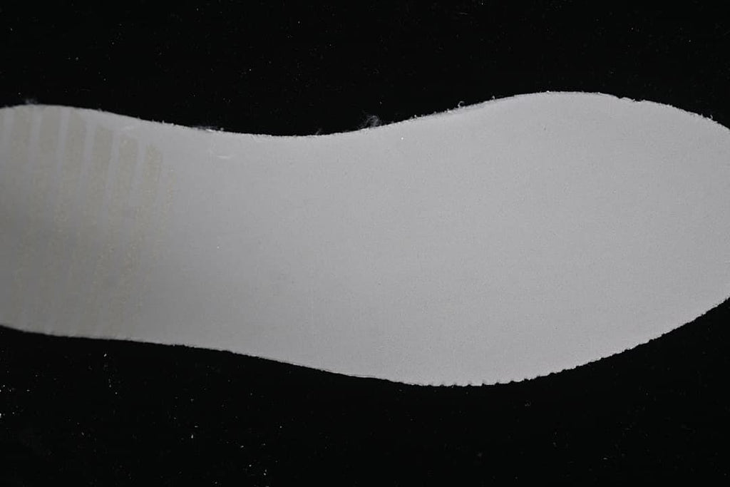 Close-up view of a plain white shoe component against a dark background.