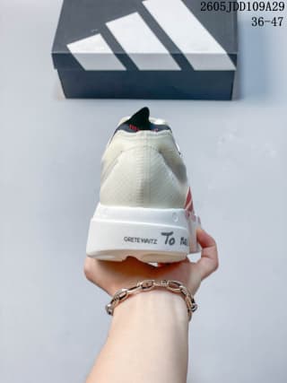 Rear view of the white and red running shoes held in front of an Adidas shoebox, showing the heel structure and sole.