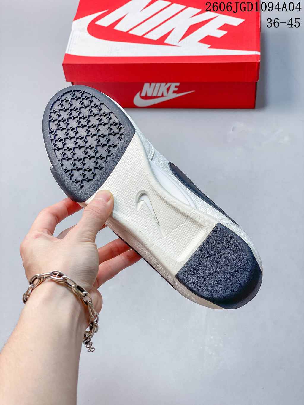 Underside of a white sneaker showing dark traction sections and a textured outsole