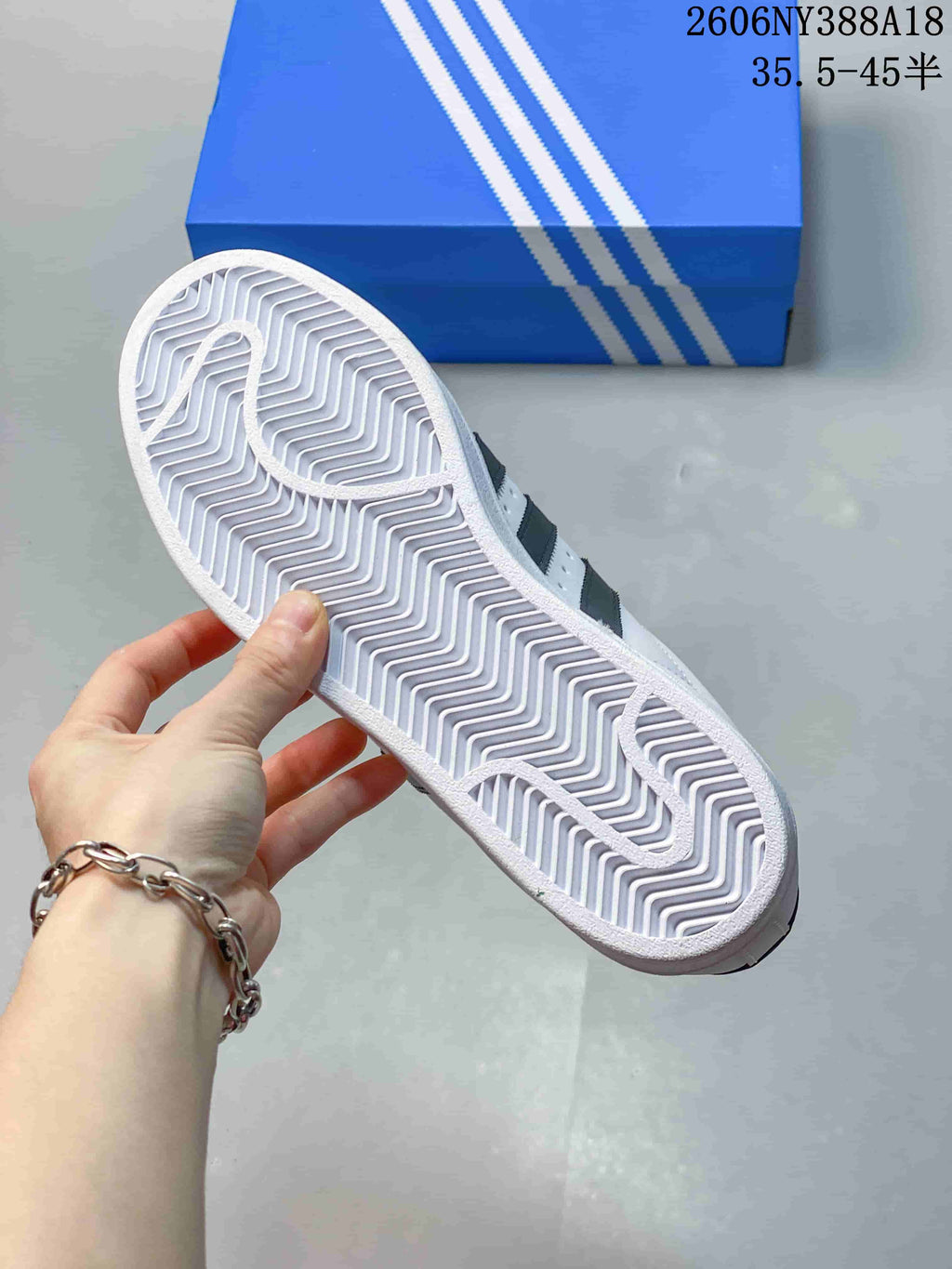 Underside of a white sneaker showing a patterned outsole.