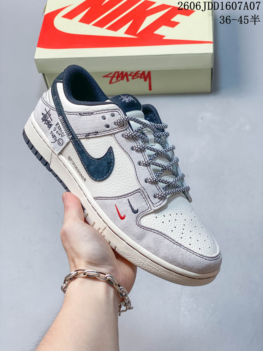 Close-up of a grey and white low-top sneaker with dark blue swoosh and small contrasting details.
