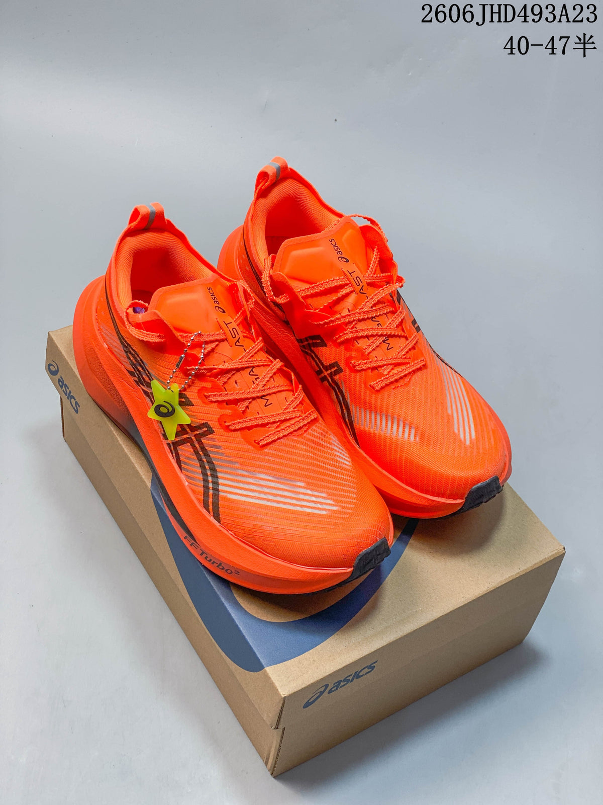 Pair of bright orange ASICS MAGIC SPEED FF TURBO running shoes on a shoebox